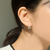 Contemporary sterling silver huggie hoops shaped in a soft triangular dome, reflecting light beautifully with their smooth, high-shine surface — a refined yet statement-making everyday earring.
