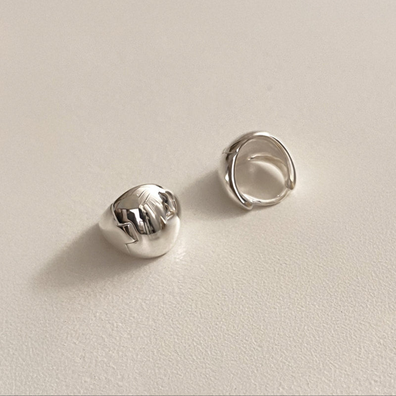 Minimalist sterling silver huggie hoops shaped like soft-edged triangles with a voluminous dome design, offering an effortlessly cool, high-fashion jewellery statement.
