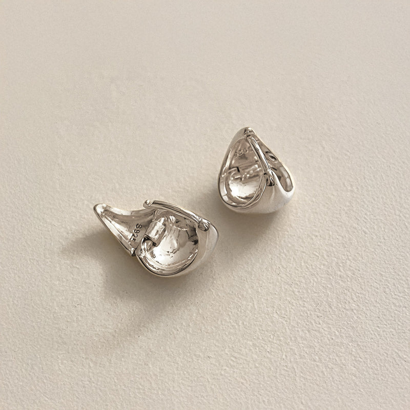 Solid sterling silver dome huggie hoops crafted in a softly angular triangle shape, designed to hug the ear with comfort while adding a contemporary sculptural detail.
