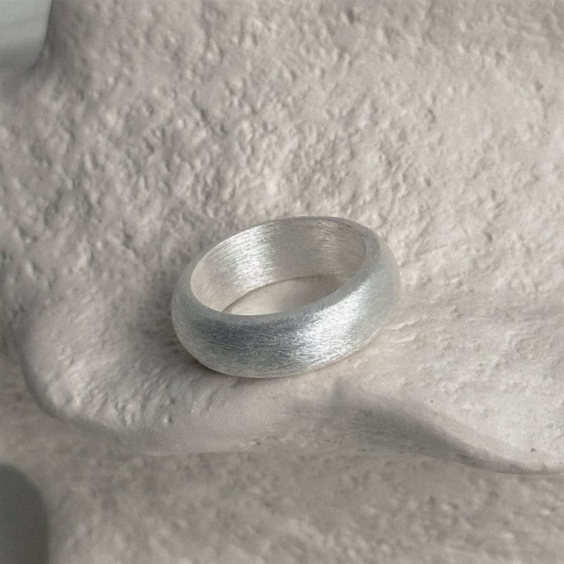 Thick sterling silver band ring in a sculptural rounded form with a muted matte finish, evoking an old money aesthetic and subtle sophistication.