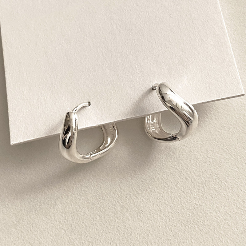 Liquid-inspired mini hoop earrings with soft, undulating curves and a reflective silver finish, adding a modern twist to classic huggie designs.