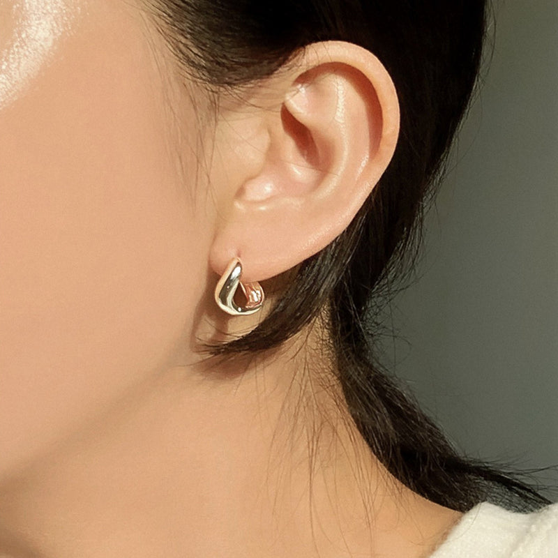 Elegant mini hoops crafted in sterling silver, shaped with a molten curve that mimics the fluidity of water for a soft yet bold look.