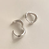 High-polish sterling silver earrings with an asymmetric liquid curve shape, offering comfort and bold simplicity in a wearable everyday design.