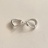 Compact sterling silver hoops with a fluid teardrop silhouette and sculptural curvature, ideal for statement wear in a minimalist form.