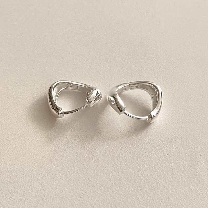 Compact sterling silver hoops with a fluid teardrop silhouette and sculptural curvature, ideal for statement wear in a minimalist form.