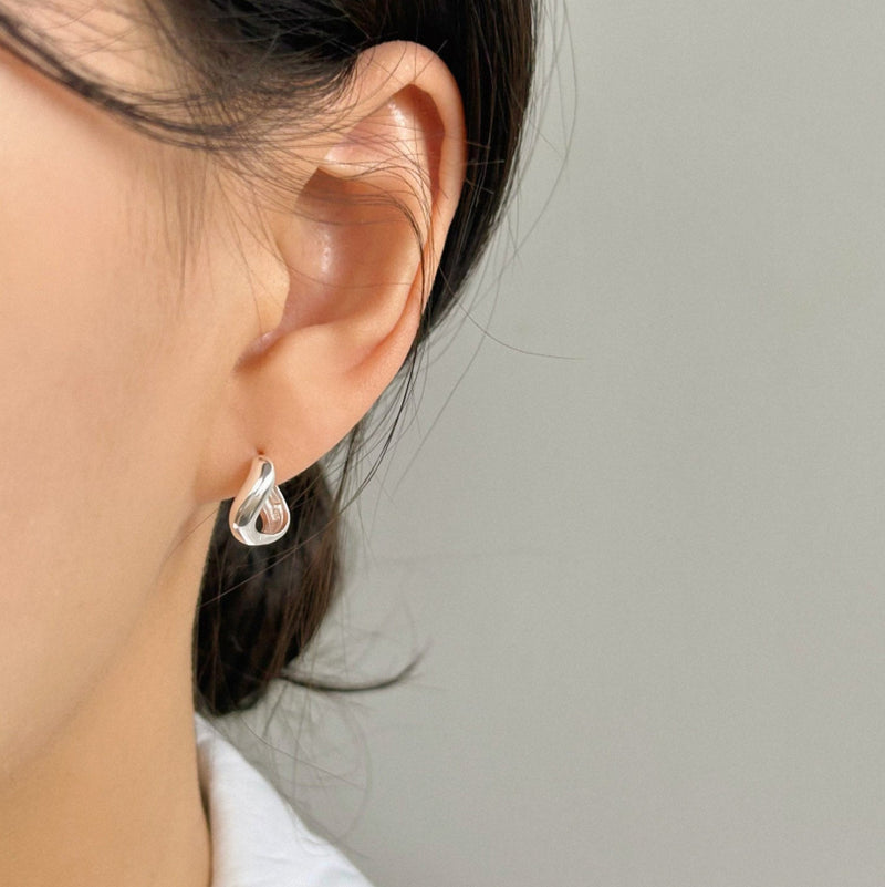Silver mini huggies formed in a molten, soft curve that evokes the look of metal in motion—sleek, artistic, and effortlessly wearable.