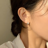 Miniature sculptural hoops in sterling silver, formed with twin teardrop domes that add depth and dimension. Designed to hug the earlobe comfortably while standing out with their artistic and bold form.