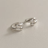 Polished sterling silver huggie hoops with twin teardrop domes, designed to give a bold, sculptural edge to your everyday jewellery. Their unique overlapping form catches the light and adds a refined statement to any outfit.
