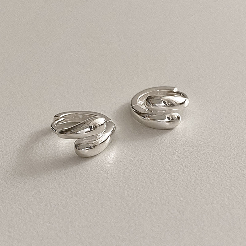 Chunky silver mini hoops with a double dome teardrop shape. These sterling silver huggie earrings feature smooth, voluminous curves that hug the earlobe, offering a modern and sophisticated look for any occasion.