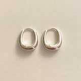 A pair of sterling silver rounded square huggie hoops with a clean, sculptural form, ideal for lovers of minimal design and refined craftsmanship.