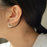 Artistic sterling silver huggie earrings with bold rounded square design, polished to a mirror finish for a sleek and elegant statement.