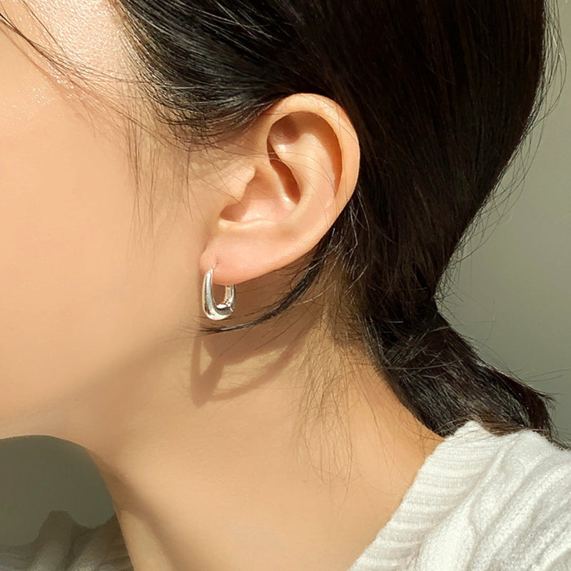 High-shine sterling silver huggie hoops featuring a smooth, cushion-like square form, perfect for elevated everyday styling or editorial-inspired looks.