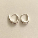Minimalist silver earrings with a chunky rounded square shape, exuding contemporary sophistication and sculptural fluidity in every angle.