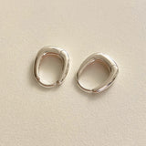 Rounded square huggie hoop earrings crafted from polished sterling silver, designed with soft geometric curves that blend elegance with artistic edge.