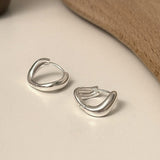 Organically shaped huggie hoop earrings made in sterling silver, designed with a droplet-inspired twist for a modern and sophisticated edge.