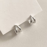 Minimalist silver mini hoops with a twin-line design that offers texture and visual interest, ideal for those seeking subtle statement earrings with a clean, modern look.

