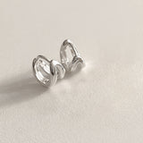 Contemporary double line huggie hoop earrings in a mini size, made from sterling silver and shaped to follow the natural curve of the ear, delivering comfort and style in one refined piece.