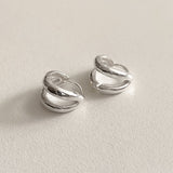 Sculptural sterling silver huggie earrings featuring two parallel lines in a sleek, compact form, designed to add a hint of edge and elegance to casual and formal outfits alike.

