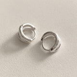 Mini double line hoops in sterling silver that hug the earlobe with polished curves, offering a modern twist on classic hoop earrings, perfect for understated sophistication.