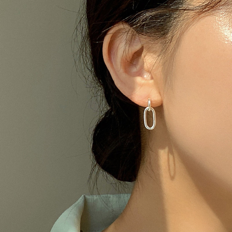 Minimalist sterling silver earrings with oval chain links in a smooth, mirror-like finish, designed to hang delicately from the earlobe for a refined yet contemporary statement.

